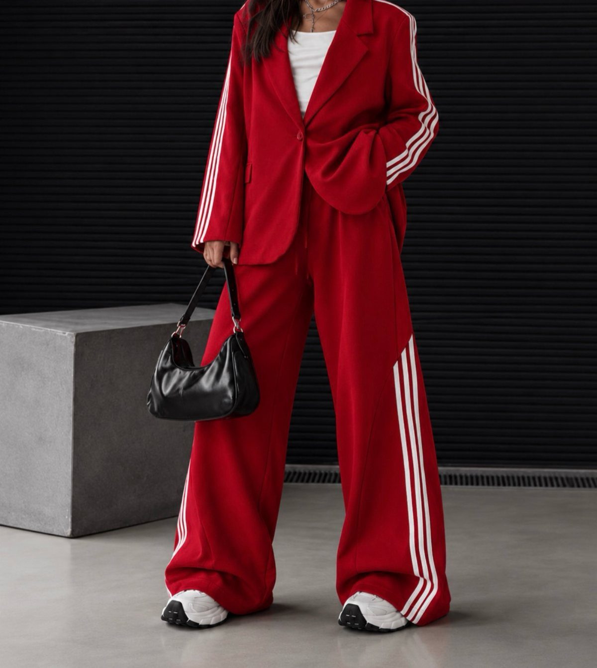 Woman in red oversized blazer and matching red track pants with white sneakers.