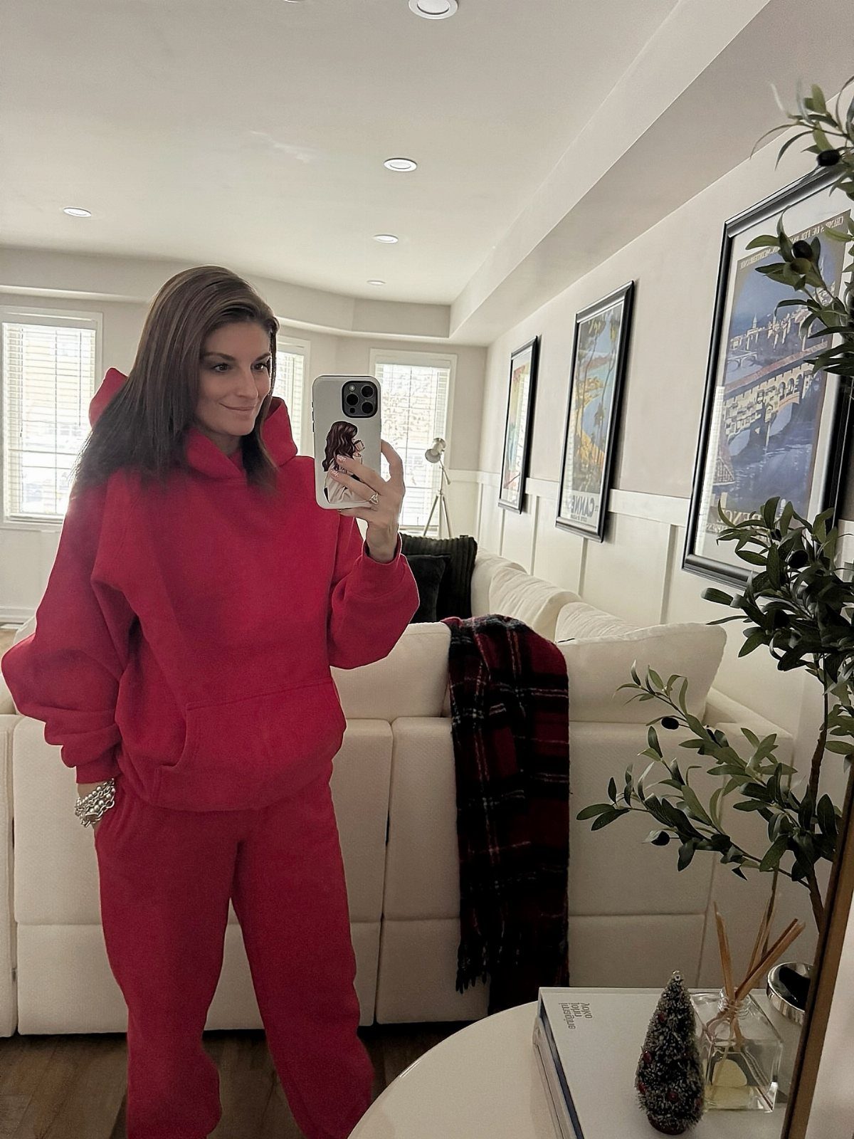 Woman wearing a red oversized hoodie and matching red track pants in a living room.