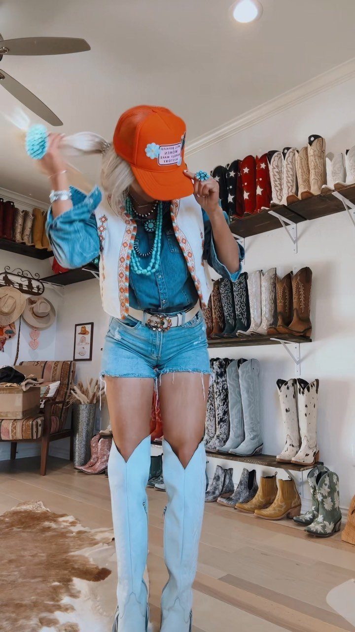 29 Rodeo Inspired Outfits Built on Fringe, Denim, and Boots 10 Person in denim shorts and light blue cowboy boots wearing a fringe vest.
