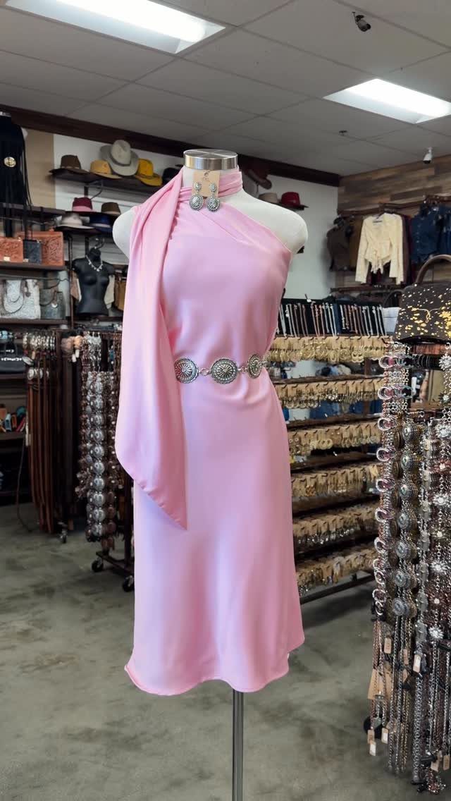 29 Rodeo Inspired Outfits Built on Fringe, Denim, and Boots 4 Pink satin dress on a mannequin with a silver ornate Western belt and scarf.