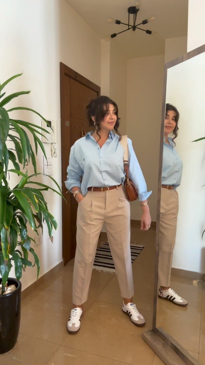 Semi Casual Clothes: 31 Outfit Ideas From Dresses to Loafers 17 Woman wearing a light blue shirt and beige trousers standing by a mirror.