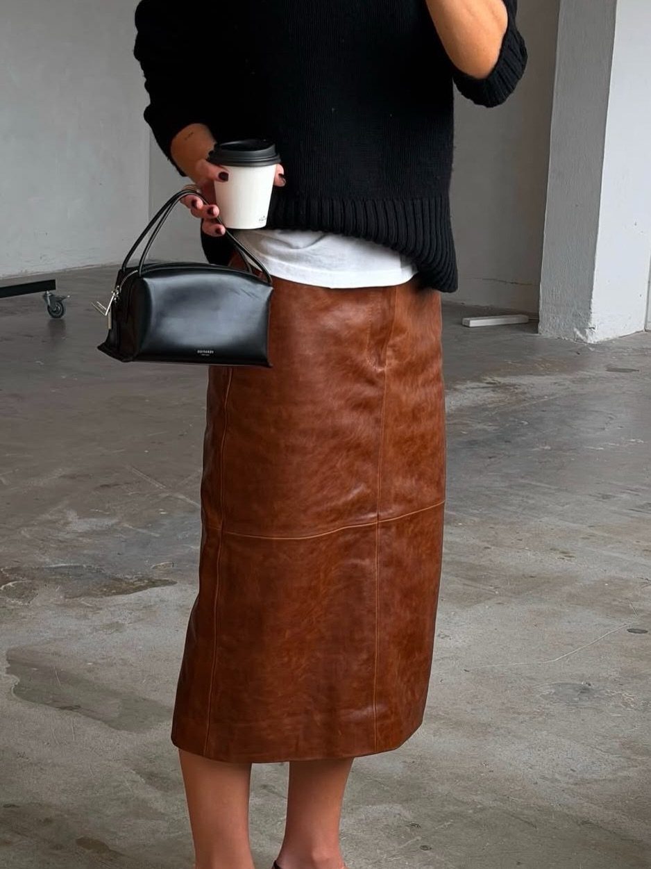 Semi Casual Clothes: 31 Outfit Ideas From Dresses to Loafers 20 Person wearing a black sweater and brown leather midi skirt holding a coffee cup