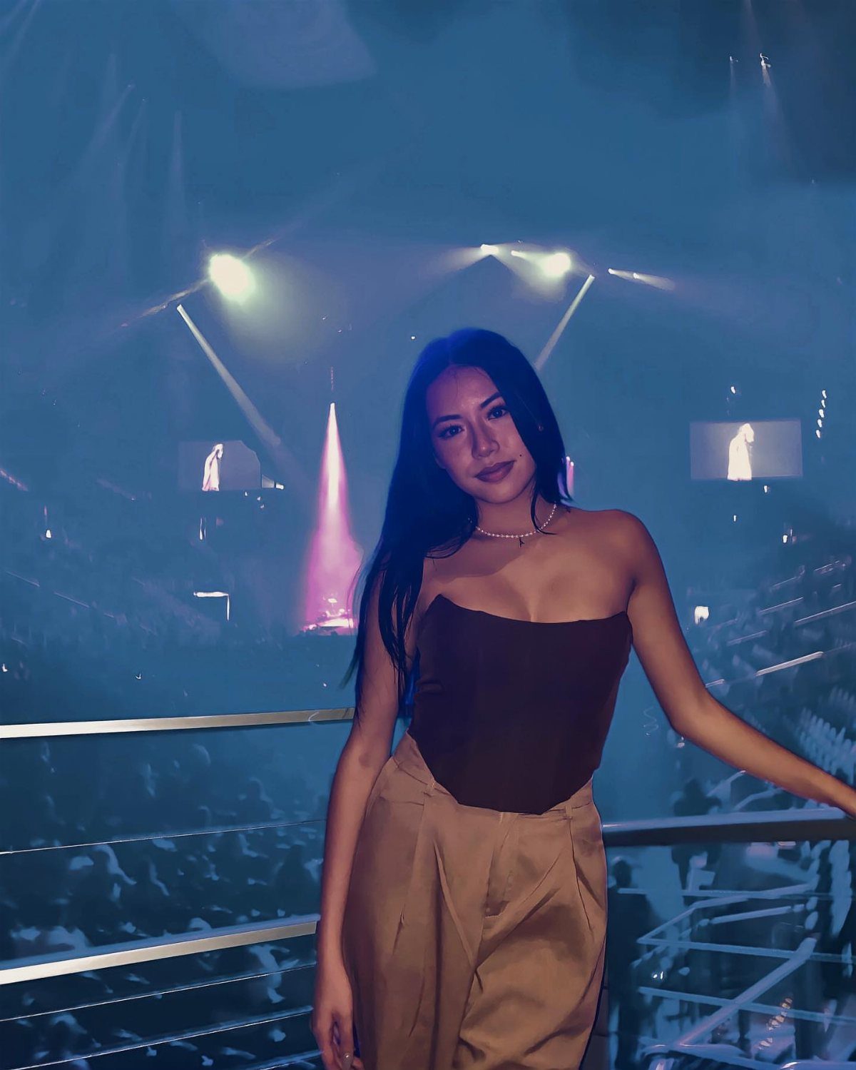 12 Seventeen Concert Outfit Ideas for Women to Stand Out 4 Woman wearing a brown strapless corset top and tan trousers at a concert venue.