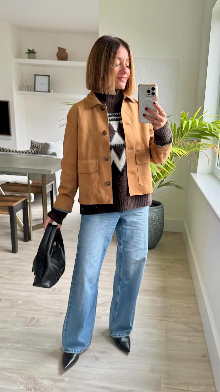 Woman wearing wide-leg light-wash jeans and black pointed-toe ankle boots in a room.