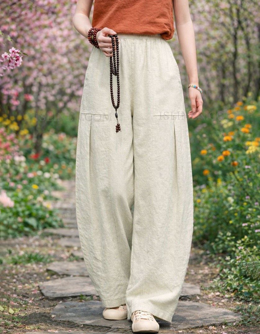 Tan Linen Pants Outfit Ideas for Women: 11 Looks to Try 11 Woman wearing wide-leg tan linen pants and rust top in a flowering garden.