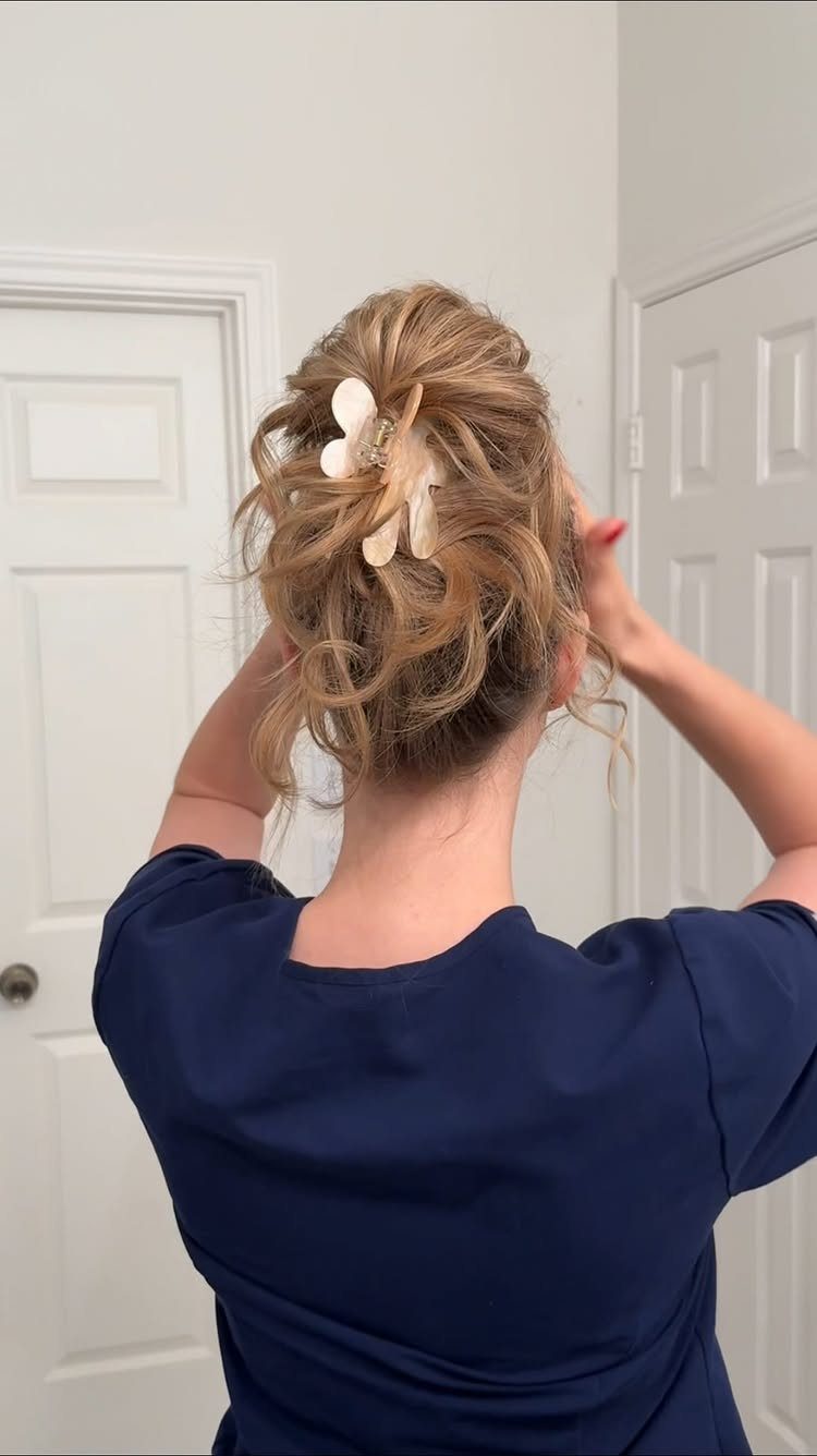 Blonde hair styled in a twisted updo secured with a flower claw clip.