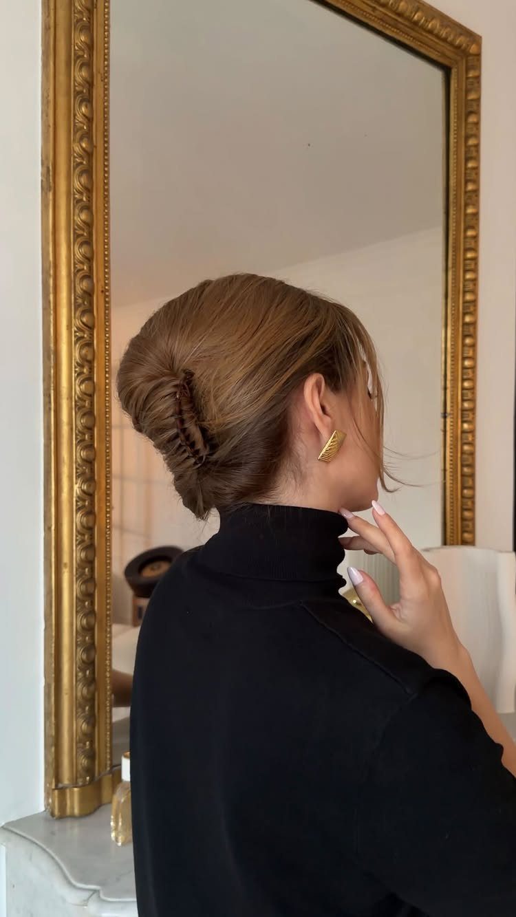 Woman with light brown hair in a French twist updo wearing a black turtleneck.