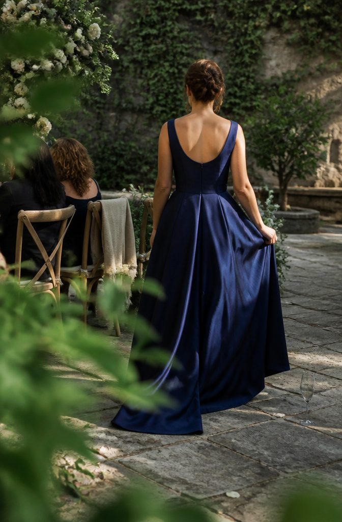 7 Ideas for Wedding Dresses Not White, From Blush to Black 10 Bride seen from behind in a deep blue dress crossing a stone courtyard