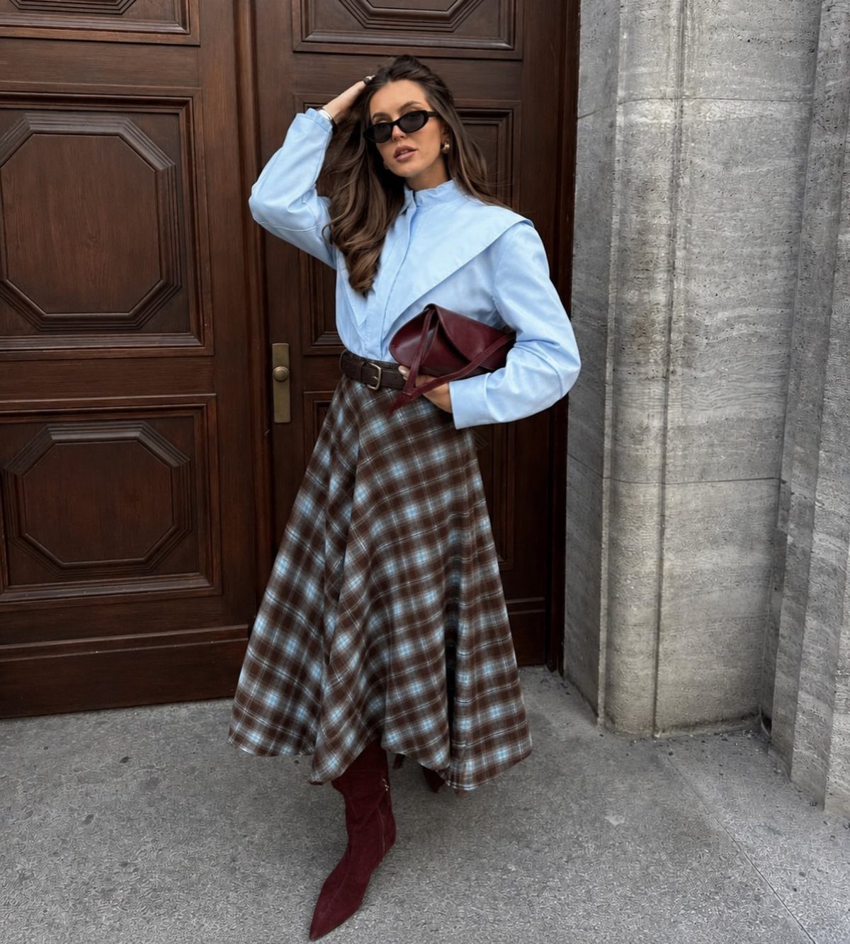 What to Wear on Broadway: 12 Ideas From Blazers to Skirts 12 Woman wearing a light blue shirt and plaid full midi skirt with burgundy boots.