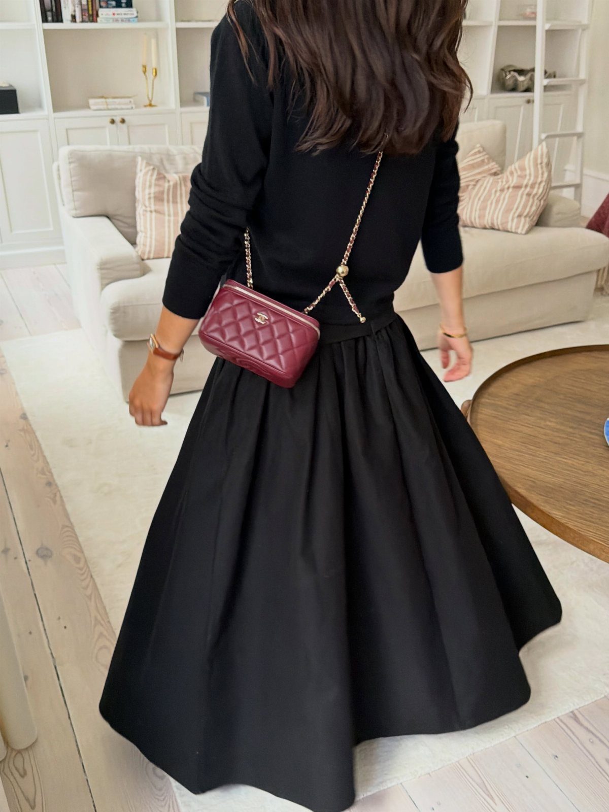 What to Wear on Broadway: 12 Ideas From Blazers to Skirts 10 Woman wearing a black sweater and black maxi skirt with a red quilted handbag.