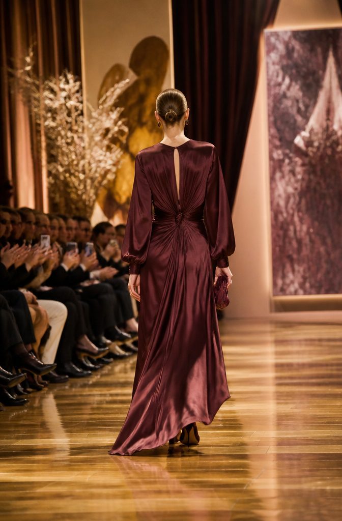 When Do Fall Dresses Come Out: A Guide to 2026 Fashion Timing 2 A model in a burgundy dress walks down a runway.