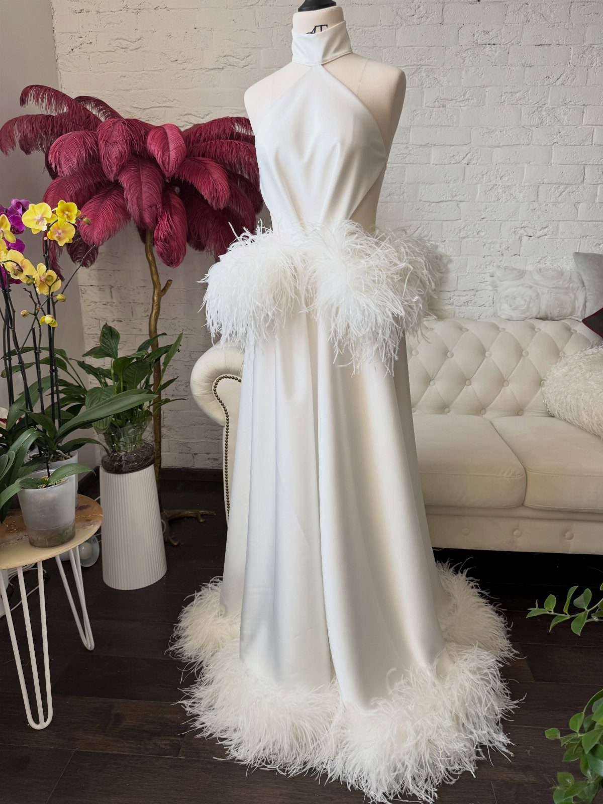 14 White Feather Gown Ideas, From Bridal Capes to Tea-Length 8 White halter-neck gown with feather accents at the waist and along the bottom hem.