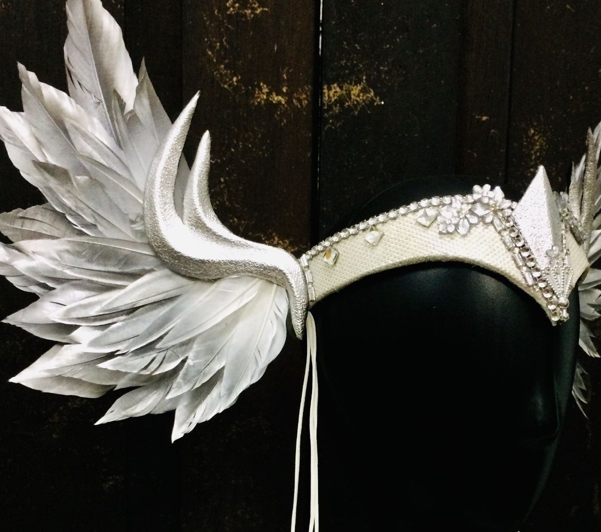 14 White Feather Gown Ideas, From Bridal Capes to Tea-Length 5 White feather wing headpiece with rhinestone detailing on a black mannequin head.
