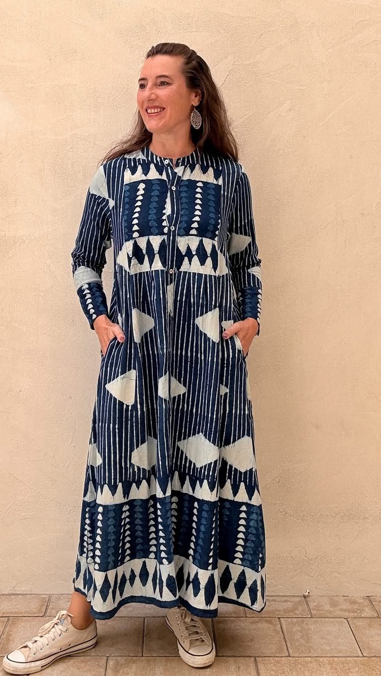 Woman in a long blue and white patterned button-down dress and white sneakers.