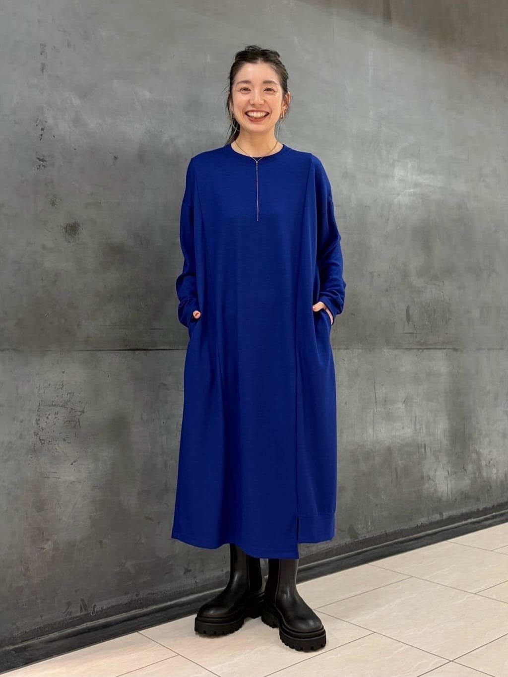Woman in a royal blue jersey midi dress with black chunky boots.