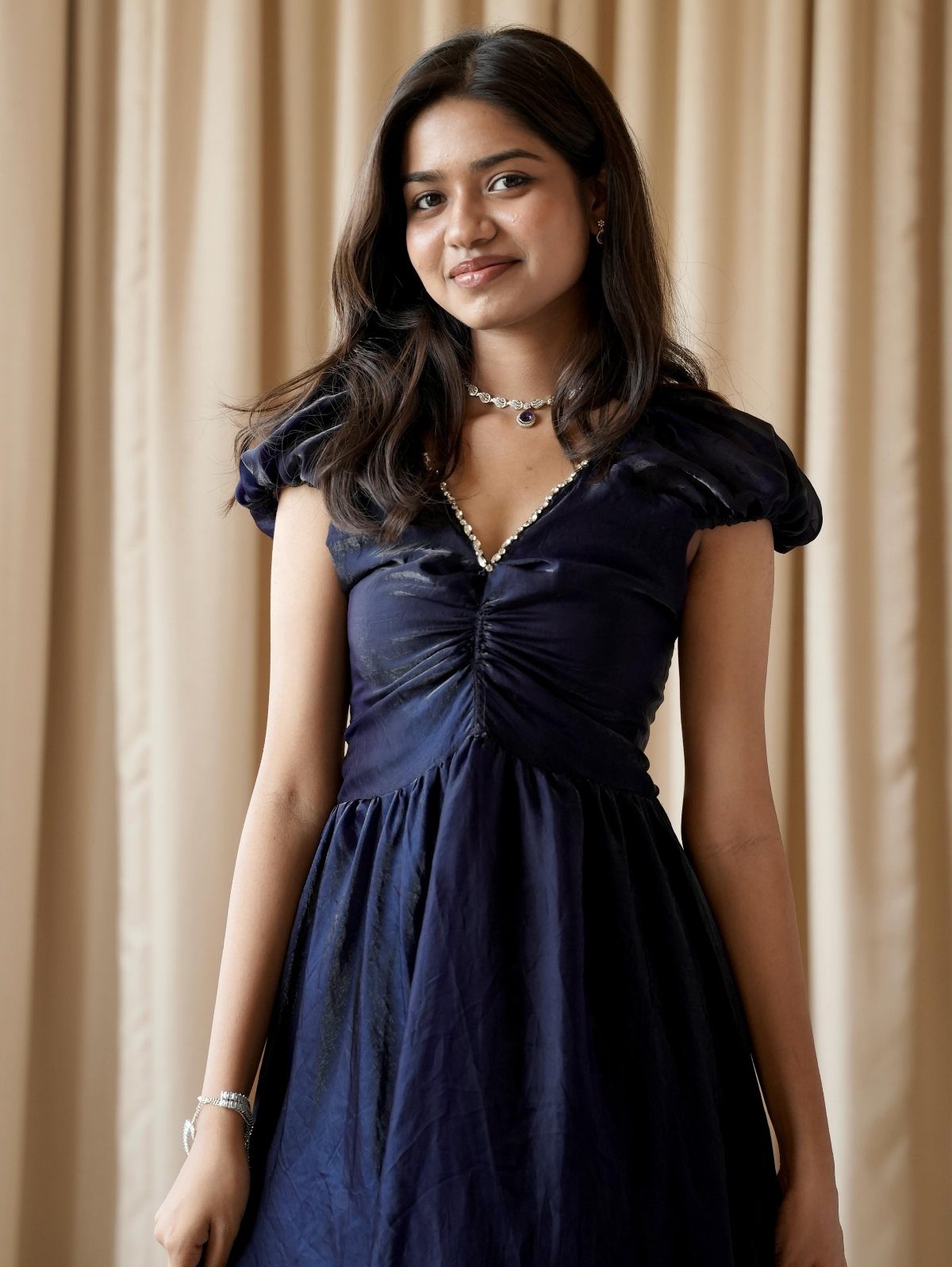 Woman wearing a navy blue dress with ruching details on the bodice.