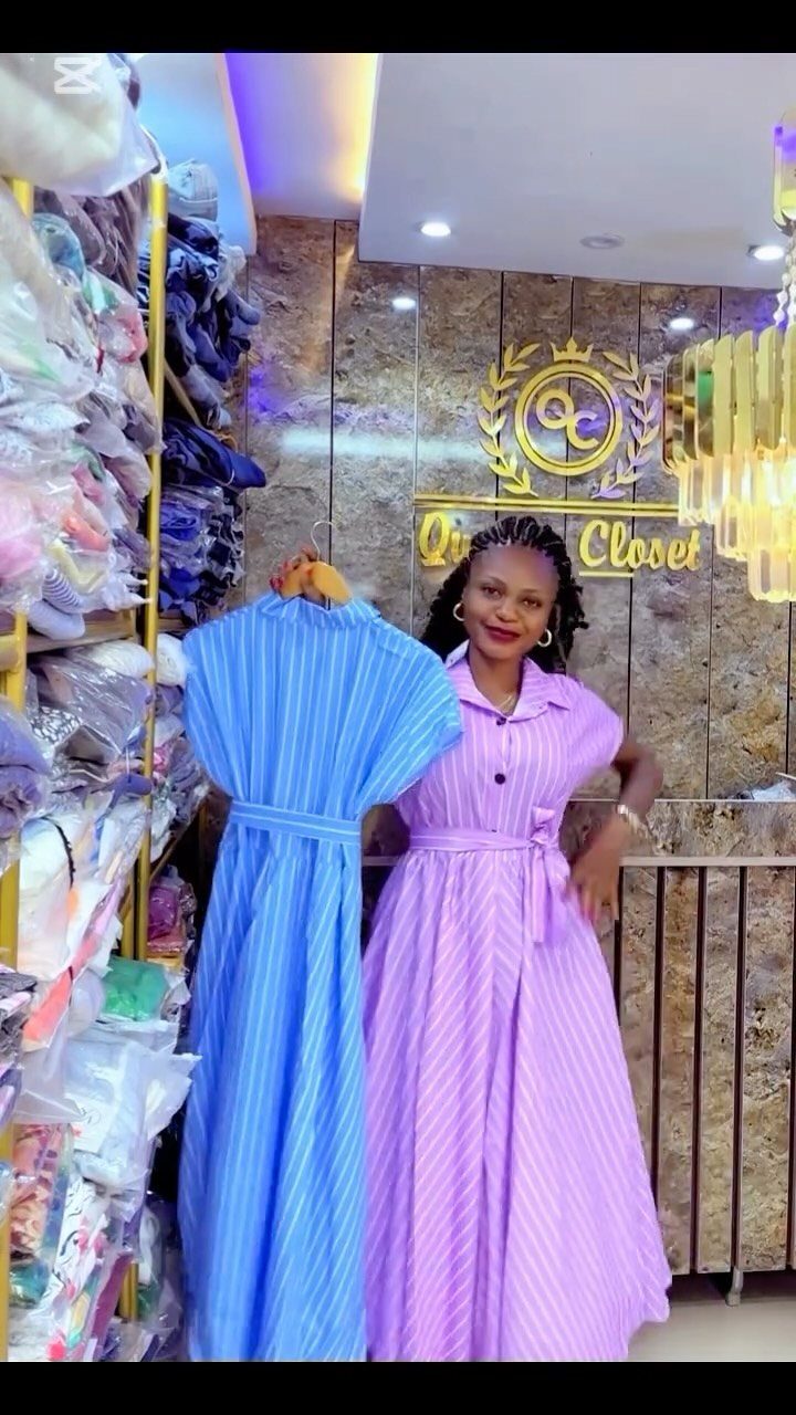Woman in purple striped shirt dress holding a blue striped shirt dress in store