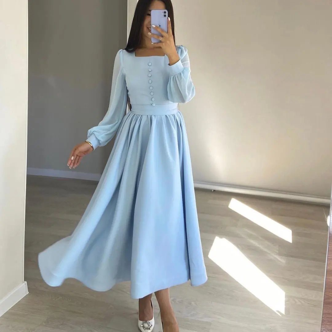Woman wearing a long-sleeved soft sky blue dress with a flared skirt.