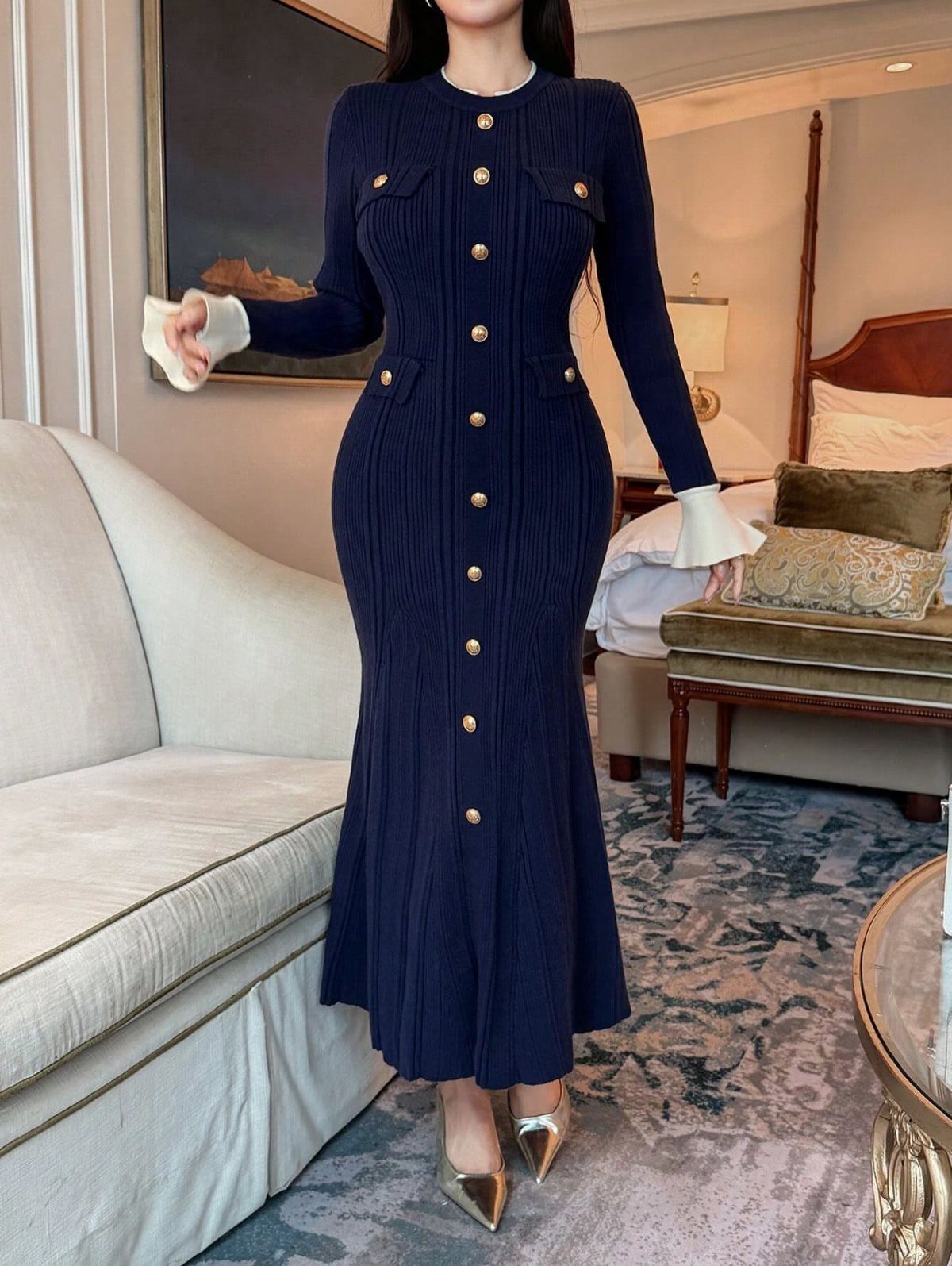 Woman in a navy blue ribbed knit dress with gold buttons and white cuffs.