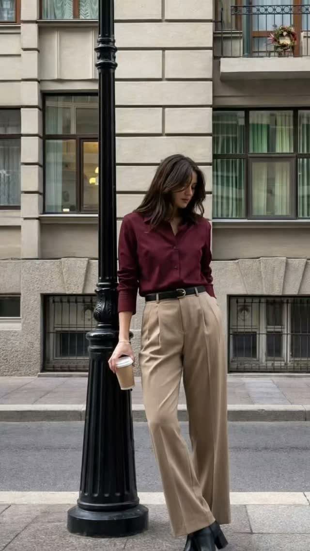 Women Outfit Work Office: 17 Ideas to Refresh Your Look 6 Woman wearing a maroon blouse and wide-legged tan trousers standing by a lamppost.