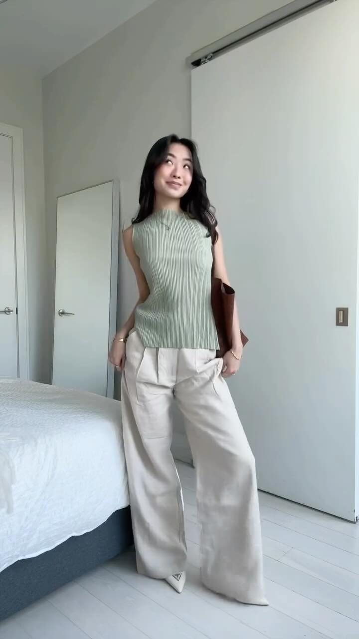 Women Outfit Work Office: 17 Ideas to Refresh Your Look 8 Woman wearing a light green sleeveless top and wide-legged beige trousers in a bedroom.