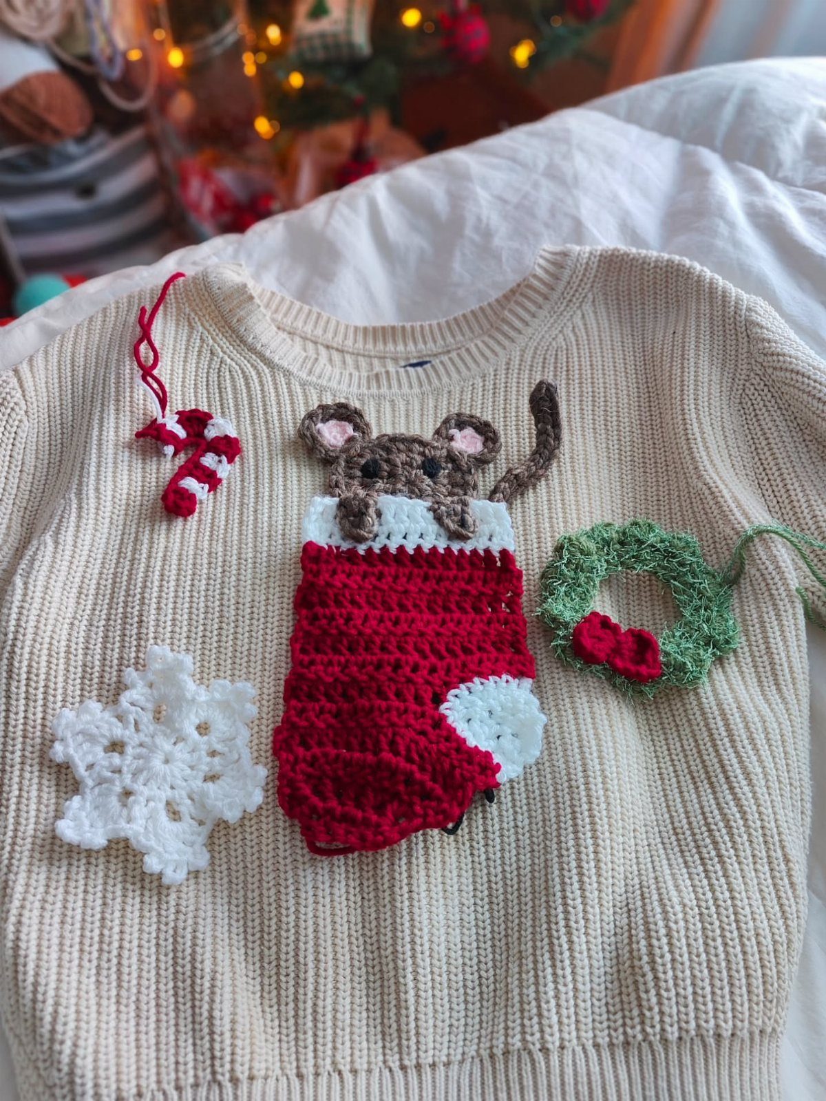 Cream ribbed sweater decorated with crochet Christmas stocking, mouse, wreath, and snowflake.