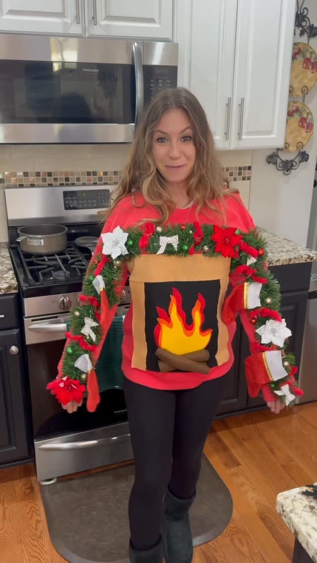 Woman wearing a red ugly Christmas sweater featuring a wreath and fireplace design.